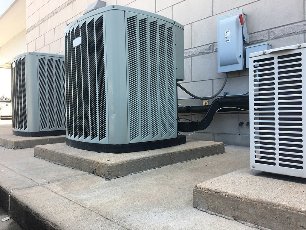 Multiple commercial air conditioning condenser units installed outside a commercial building